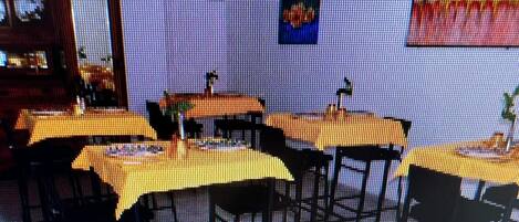 Un interior de restaurante con mesas y sillas, una zona de bar y una pared con un cuadro.