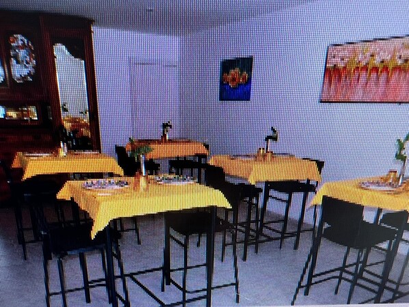 A restaurant interior with tables and chairs, a bar area, and a wall with a painting. - B&B Garden Grazia (Noto)
