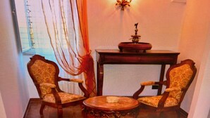 Ein Zimmer mit zwei Holzstühlen, einem kleinen runden Tisch und einem roten Beistelltisch mit einem dekorativen Gegenstand.