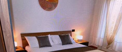 A hotel room with a bed, a nightstand, a lamp, and a wall art piece.