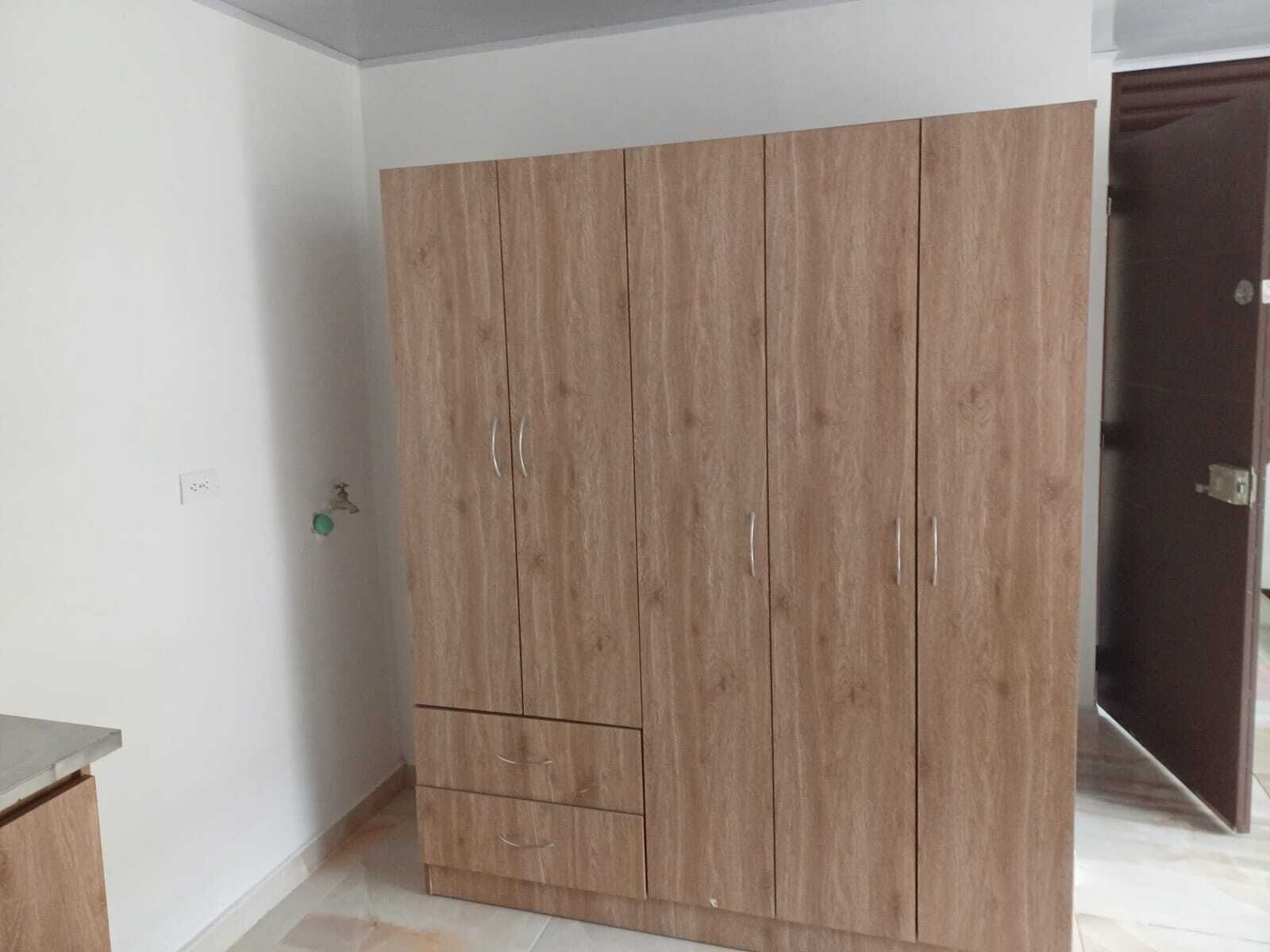 Quarto com um guarda-roupa de madeira grande, um armário pequeno e soalho em azulejos.