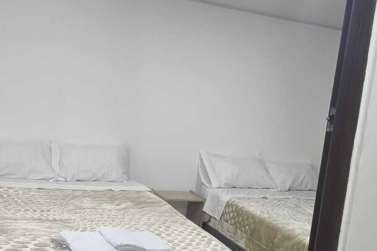 A hotel room with two beds, white bedding, and a ceiling with recessed lighting.