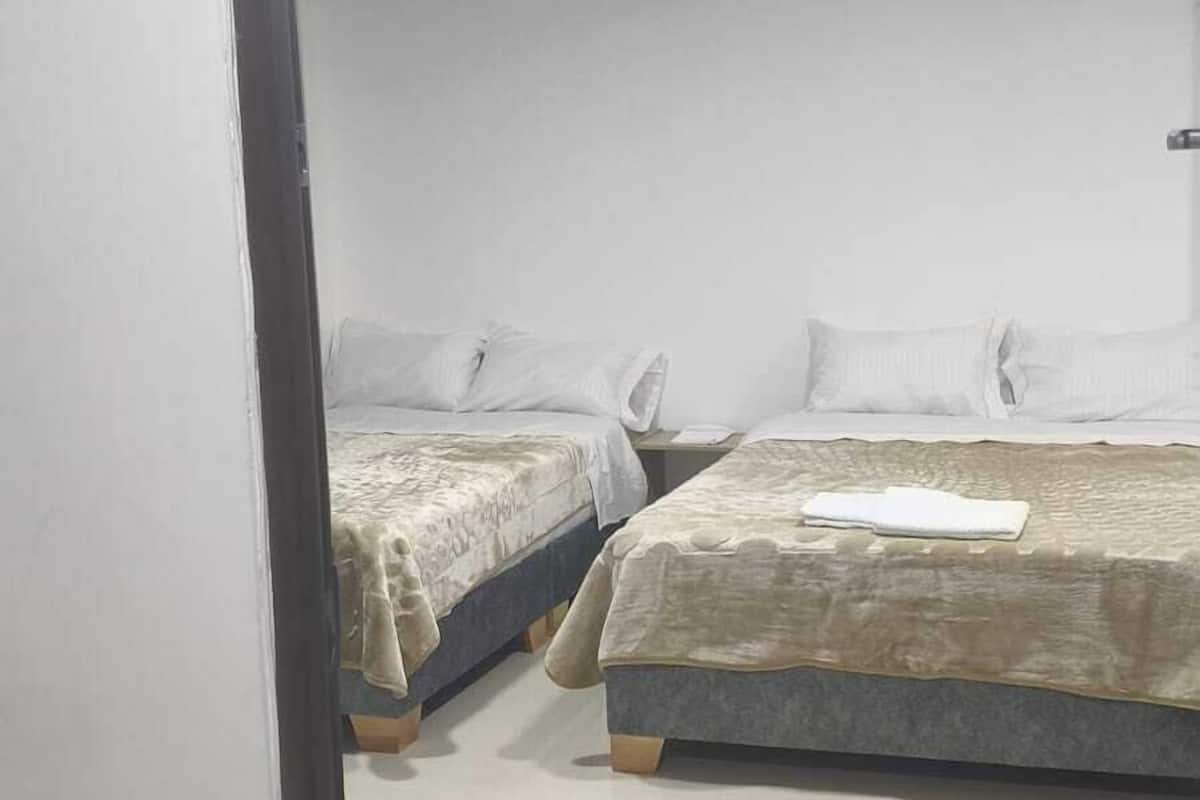 A room with two beds, a tiled floor, and a number sign above the door.