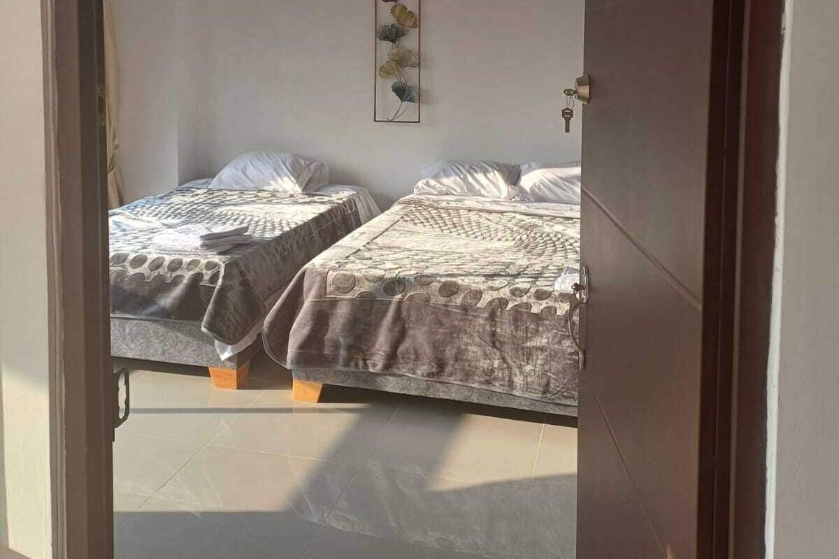 A room with two beds, a door with a number sign, and a wall-mounted key.