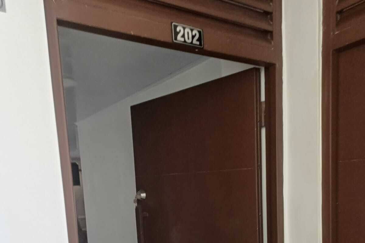 A closed brown door with a number plate '202' above it.