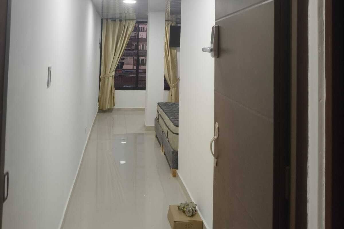 A hallway with a door labeled 402, a bed, a window with curtains, and a box on the floor.