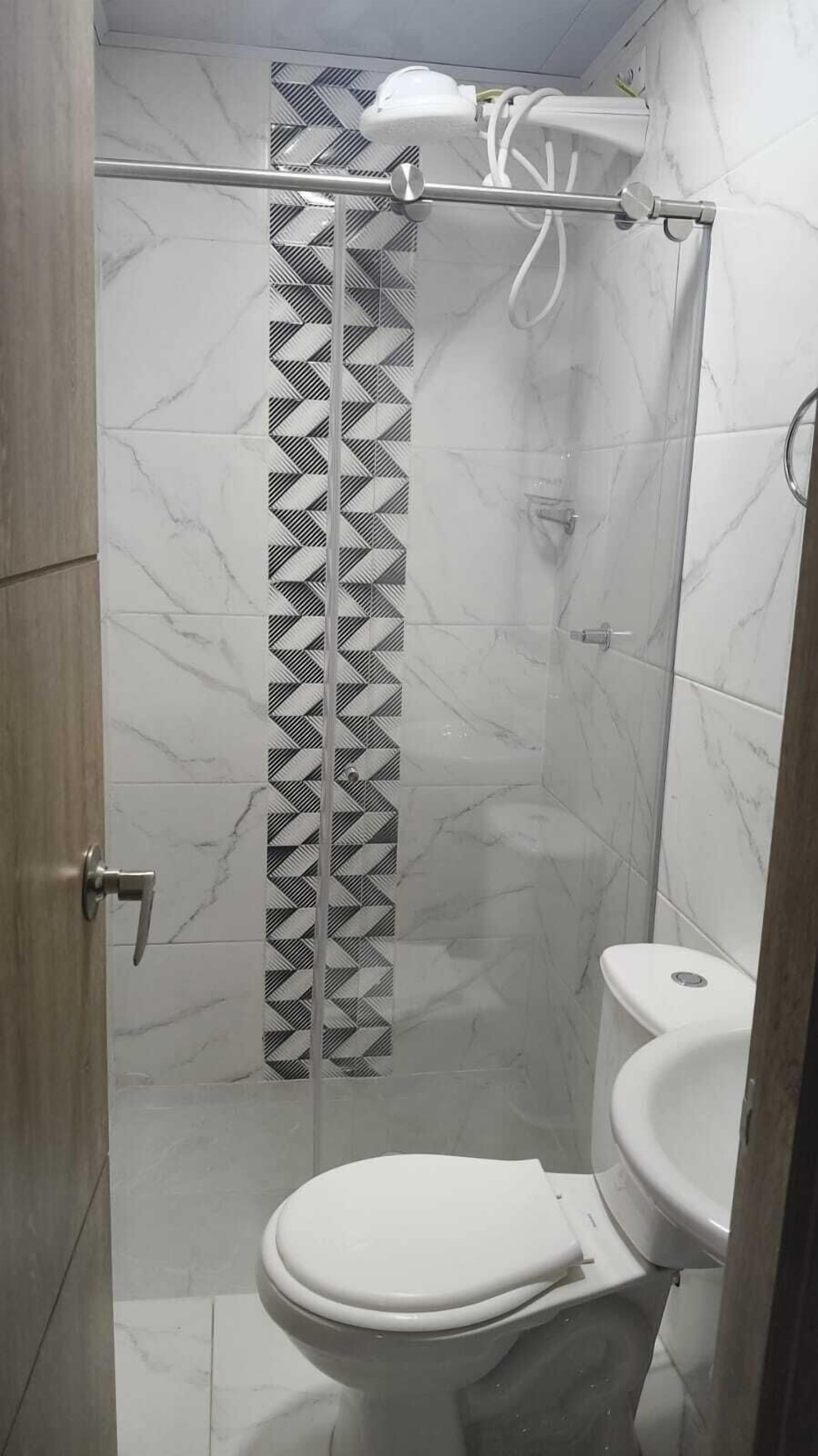 A bathroom with a shower, toilet, and a patterned curtain.
