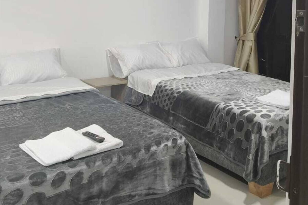 A hotel room with two beds, white bedding, a number '401' sign, and a curtain on the window.