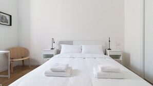 A neatly made bed with white linens and two folded towels, a wooden chair, and two bedside tables with lamps. - Italianway Collection - Panfilo Castaldi 28 (Milan)