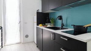 Una cocina moderna con gabinetes negros, encimera blanca y salpicadero verde azulado.
