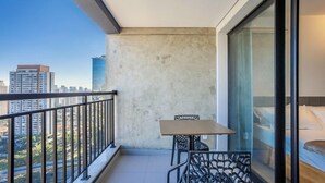 A balcony with a table and chairs, a view of the cityscape, and a large window. - Apt w/ Balcony, Minutes From the Subway Ctb2405 (São Paulo)