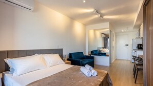 A hotel room with a bed, a desk, a chair, and a kitchenette. - Apt w/ Balcony, Minutes From the Subway Ctb2405 (São Paulo)