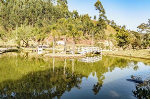 A serene pond with a white bridge, surrounded by lush greenery and trees. - Casa de Campo c Lareira Jogos e Piscina Aquecida (Anitapolis)
