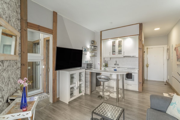 A modern kitchen with white cabinets, a black TV, and a bar area.