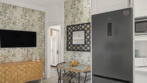 Une cuisine moderne avec des meubles en bois, un réfrigérateur noir, une table à manger avec un chemin de table à rayures et un élément décoratif mural.