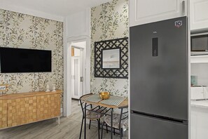 A modern kitchen with a wooden cabinet, a black refrigerator, a dining table with a striped placemat, and a decorative wall piece.