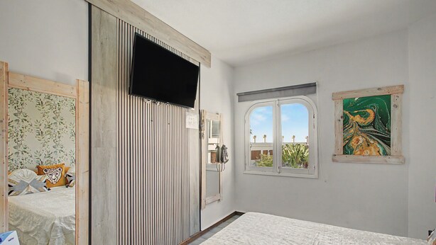 Une chambre à coucher avec un lit, une armoire, une fenêtre donnant sur un beau paysage et un tableau accroché au mur.