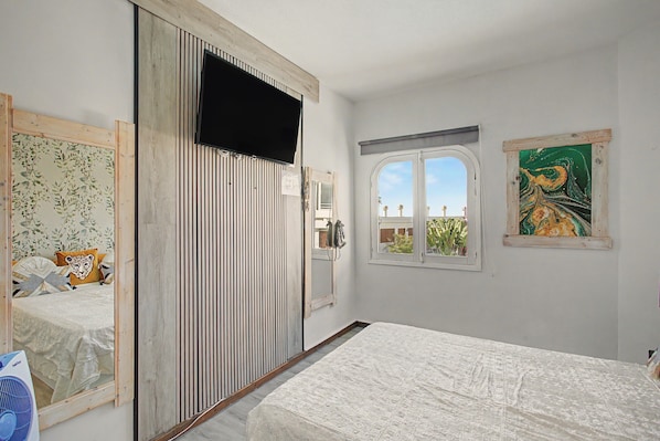 A bedroom with a bed, a wardrobe, a window with a view, and a painting on the wall.