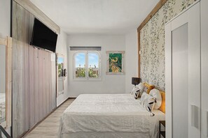 A bedroom with a bed, a window, and a wall with a floral pattern. - Apartment Two Minutes from the Beach. Puerto Rico (Mogán)