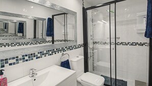 A bathroom with a white sink, a toilet, a glass-enclosed shower, and a mirror above the sink. - Apartment Two Minutes from the Beach. Puerto Rico (Mogán)