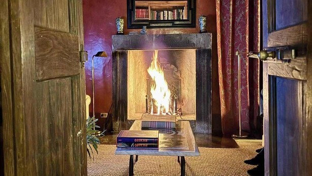 A cozy room with a fireplace, books on a table, and a mirror above it. - New Estate of Joy a Magnificent Historic Villa Near Rome on Glorious Ground Pool and Olives Galore (Ronciglione)