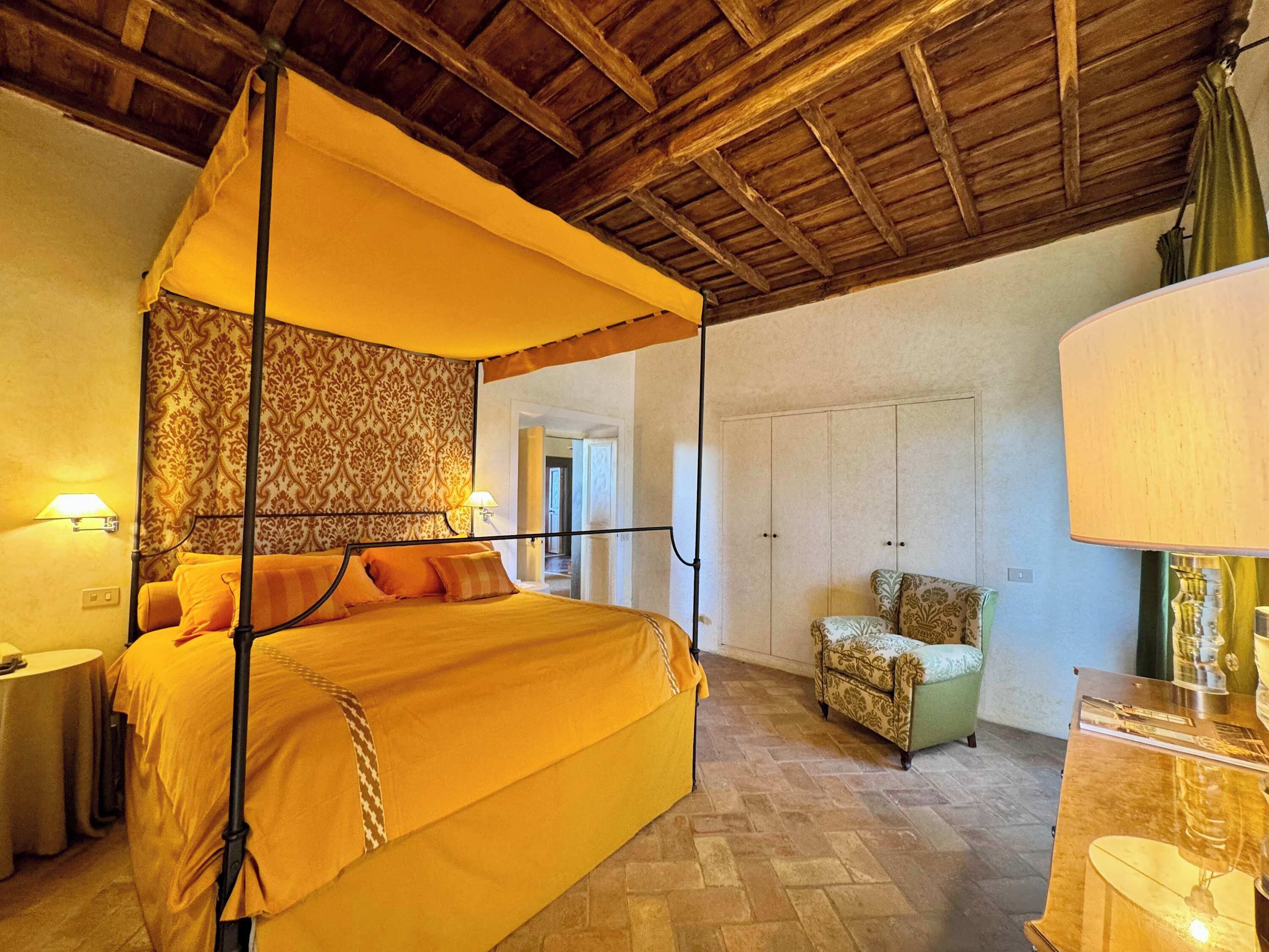 Une chambre avec un lit sous un dais, une chaise, une table et une armoire.