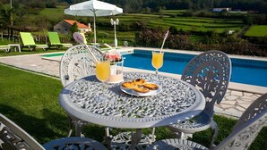A poolside table with a plate of pastries, two drinks, and a white umbrella. - Villa 'Casa Dos Leões' with Mountain View, Private Pool and Wi-Fi (Ponte de Lima)