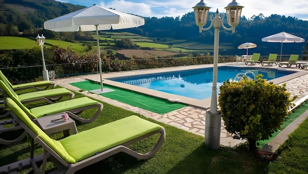 A pool area with lounge chairs, umbrellas, and a view of the surrounding landscape. - Villa 'Casa Dos Leões' with Mountain View, Private Pool and Wi-Fi (Ponte de Lima)