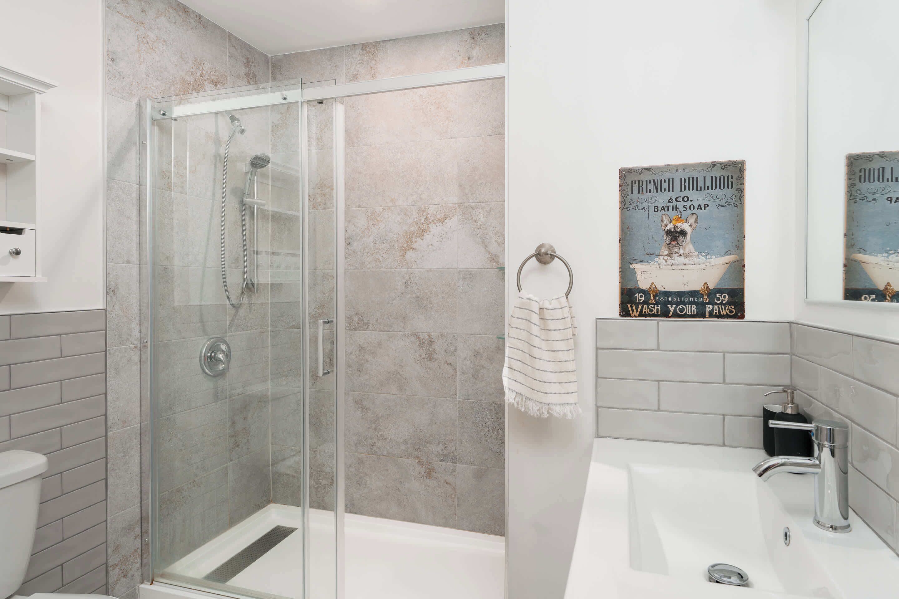 A modern bathroom with a glass-enclosed shower, a white sink, and a towel rack.
