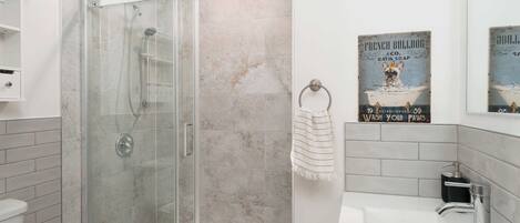 A modern bathroom with a glass-enclosed shower, a white sink, and a towel rack.