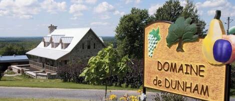 Señal de Domaine de Dunham, con un rústico edificio de piedra al fondo.
