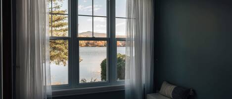 A bedroom with a large window, a bed, and a nightstand.