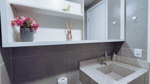 A bathroom with a sink, mirror, and shelves with decorative items.