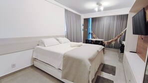 Une chambre d’hôtel avec un lit, une télévision, un hamac et une petite table.