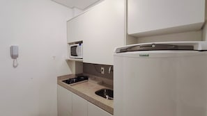 A small kitchenette with a microwave, a gas stove, and a sink. - Villa Del Porto - Porto de Galinhas (Ipojuca)