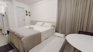 A hotel room with a bed, a bedside table, a chair, and a door. - Villa Del Porto - Porto de Galinhas (Ipojuca)