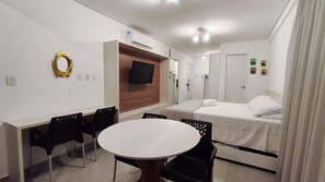 Une chambre d’hôtel comprenant un lit, une télévision, un bureau avec des chaises et une table ronde.