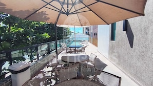An outdoor patio with a pool, lounge chairs, and a table under a large umbrella.