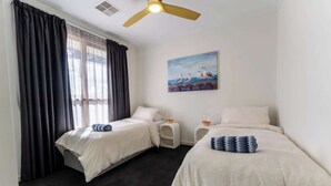 A hotel room with two beds, a ceiling fan, a painting of seagulls, and a window with curtains. - Grange Retreat - Beach, BBQ (Grange)