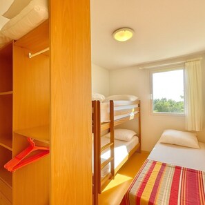A bunk bed room with a window, a bed with a striped blanket, and a wooden wardrobe. - La Terrasse du Mas, 5 guests Pool in Gard (Calvisson)
