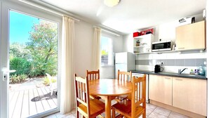 A modern kitchen with a dining table and chairs, a microwave, and cabinets. - La Terrasse du Mas, 5 guests Pool in Gard (Calvisson)