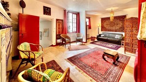 A spacious living room with a sofa, two chairs, a coffee table, and a patterned rug.