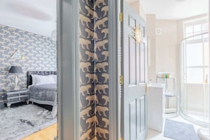 Un dormitorio con cama, mesita de noche, lámpara y pared con diseño.