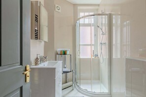 Ein modernes Badezimmer mit einer Duschkabine aus Glas, einem weißen Waschbecken und einem Spiegel darüber.