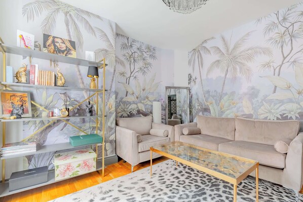 A living room with a sofa, coffee table, and a bookshelf with decorative items.