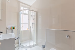 A modern bathroom with a glass shower enclosure, a white sink, and a toilet.