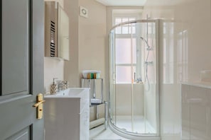 Un baño moderno con cabina de ducha de vidrio, un lavabo blanco y un espejo encima.