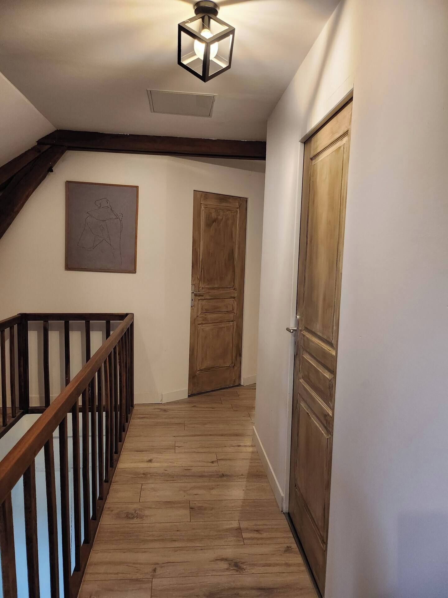 A wooden staircase with a handrail, a wooden door, and a light fixture on the ceiling.