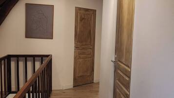 Un escalier en bois avec une rampe, une porte en bois et un luminaire au plafond.