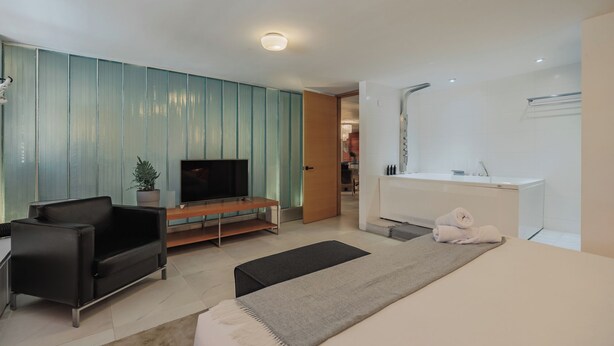Ein modernes Wohnzimmer mit Flachbildfernseher, einer Couch, einem Couchtisch und einem kleinen Teppich.